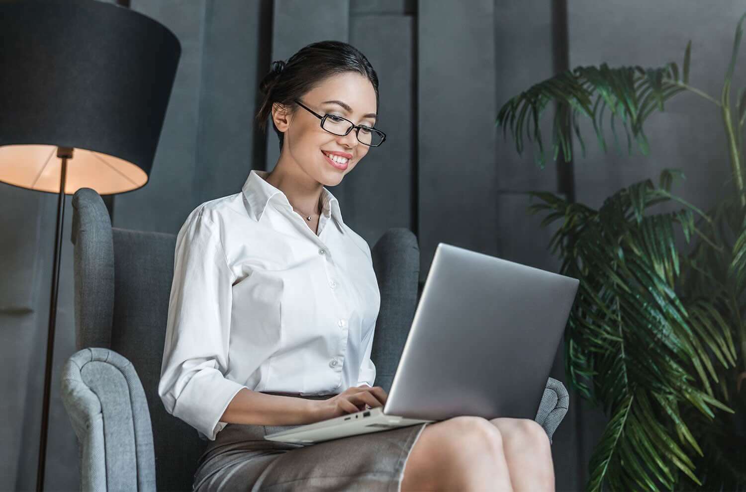 smiling young professional business woman executive wearing suit looking at laptop computer