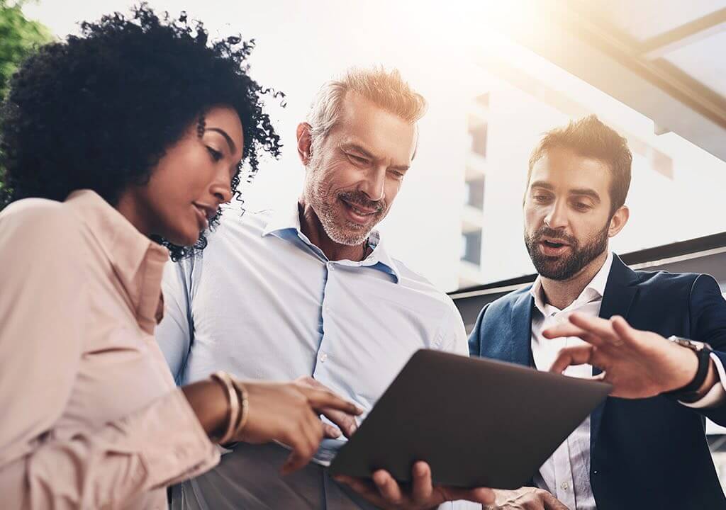 three people looking at a laptop discussing something